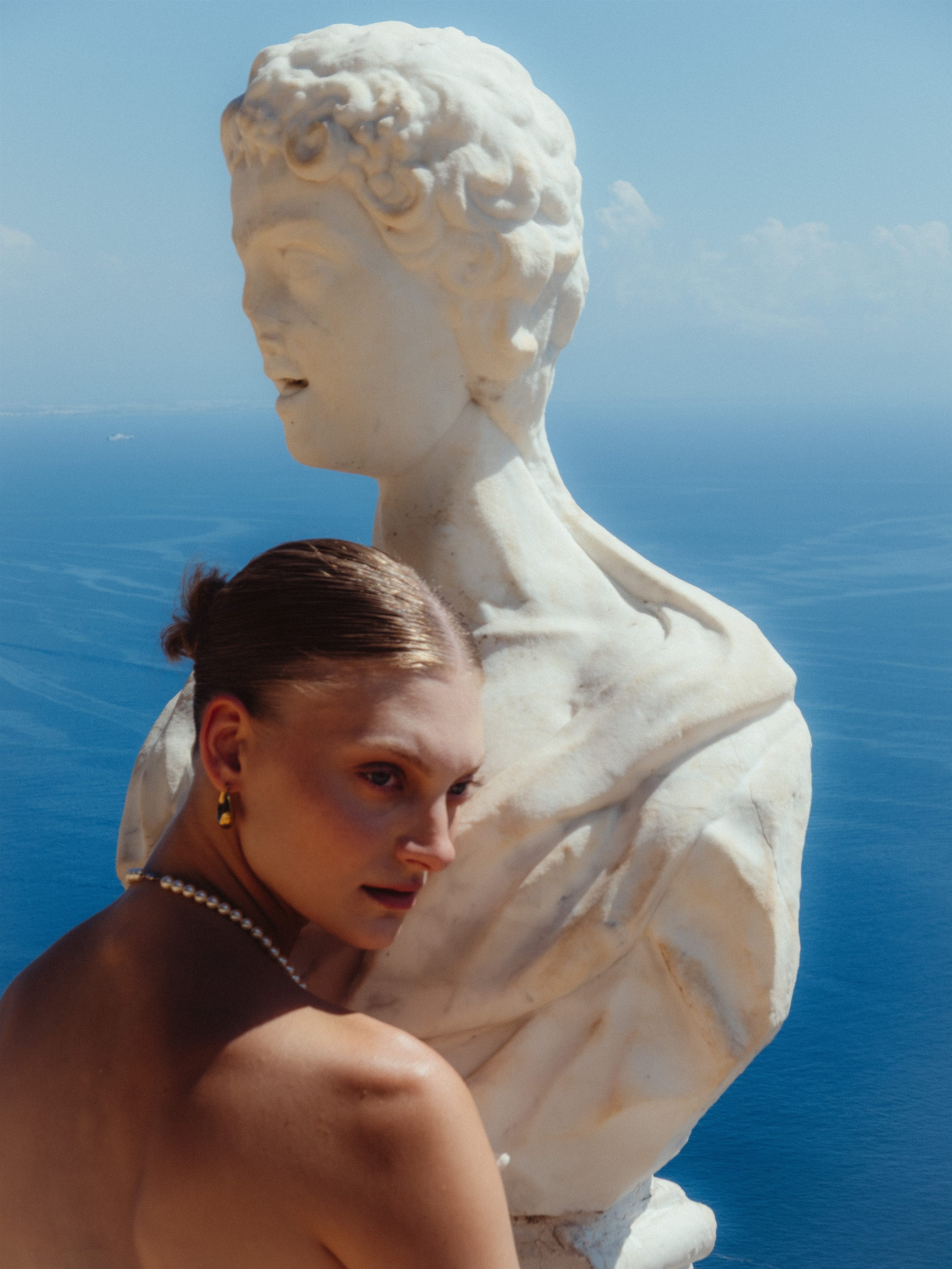 Fashion portrait beside a classical sculpture over the sea
